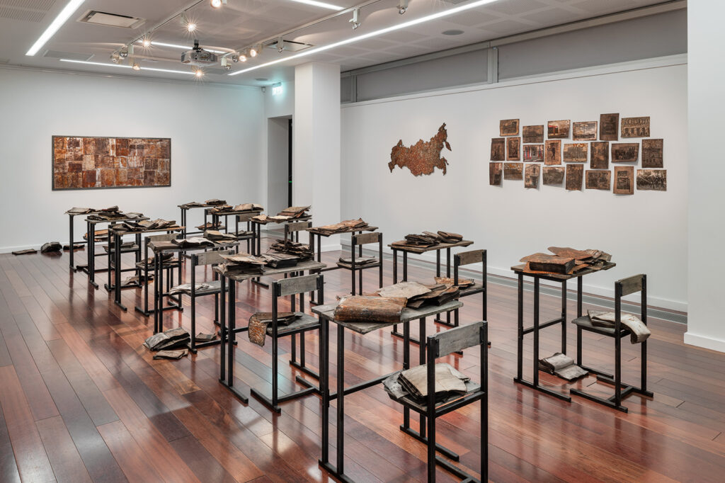 3+5. Handmade desks, chairs, rusted and stained books, prints and photographs, metal board, map. LHQ Gallery, Cork County Library. 2024